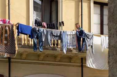 Sicilya, İtalya - 08 Ocak 2016: Catania'da balkonda kıyafet asan kimliği belirsiz kadın.