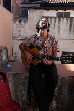 Sicilya, İtalya - 05 Şubat 2016: Catania'da balkonda gitar çalan kimliği belirsiz adam duruyor.