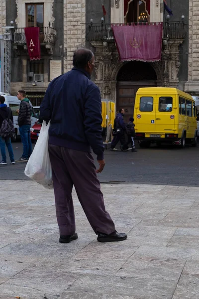 Sicilya, İtalya - 12 Ocak 2016: Sicilya'nın Catania şehir merkezindeki Piazza Duomo'da çantalı kimliği belirsiz adam.