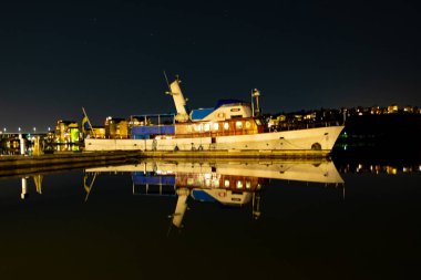 Stockholm, İsveç - 09 Mart 2016: Stockholm'de gece boyunca göl kenarında demirli teknenin görünümü.