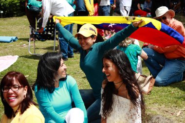 Merida, Venezuela - 21 Mayıs 2017: Yerel halk boş zamanlarında parkta eğleniyor. Venezuela ulusal bayrağını neşeyle tutan genç bir kadın.