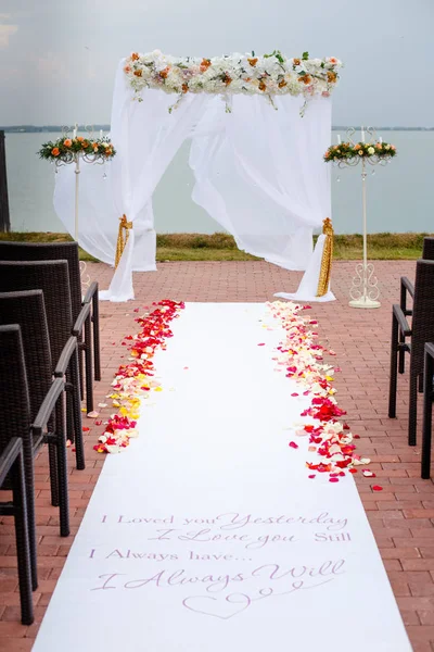 Cérémonie de mariage Arc décoré avec des arrangements floraux sur la pelouse verte et l'eau avant — Photo