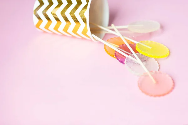Piruletas multicolores sobre un fondo rosa en un vaso de papel dorado con copyspace — Foto de Stock
