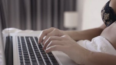 Yatakta dizüstü bilgisayarda çalışan kadın.