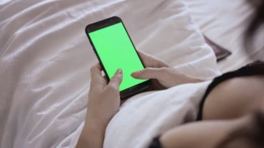 Yeşil ekran ile smartphone ile yatakta kadın