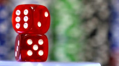Kendi ekseni etrafında dönen kırmızı zar. Arka planda Poker fişleri.