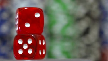 Kendi ekseni etrafında dönen kırmızı zar. Arka planda Poker fişleri.