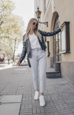 Stylish blogger posing in the street, wearing jacket.  clipart