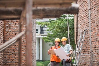 Şantiye içinde duran iki inşaat işçisi