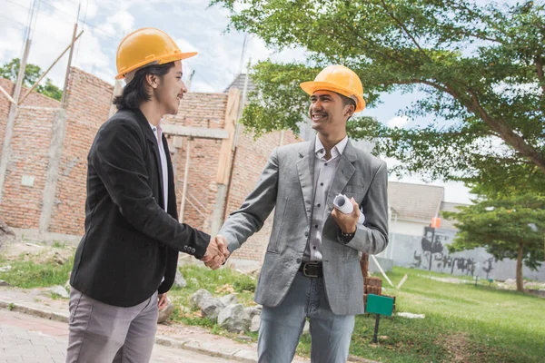 Diseñadores discutiendo plan de construcción estrechando la mano — Foto de Stock