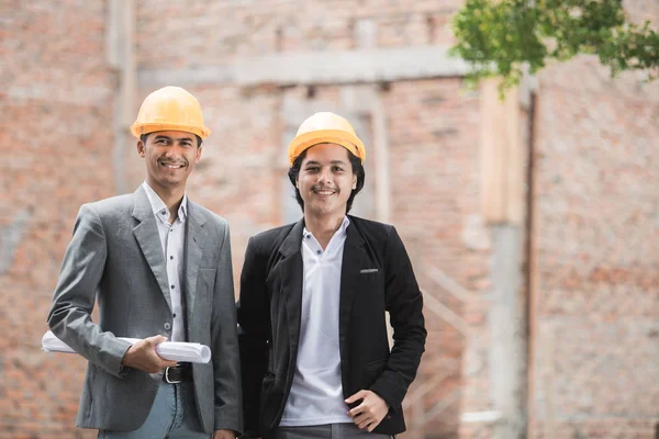 architect and builder standing in front of unfinished house