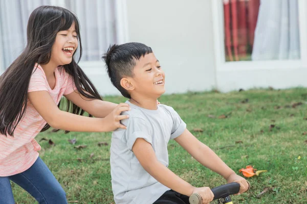 孩子骑自行车推他的妹妹 — 图库照片