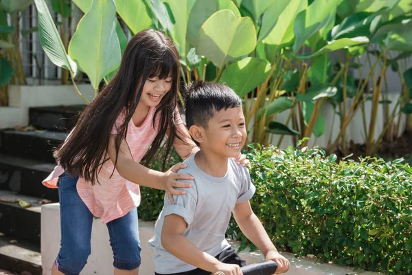 Ребенок веселится с сестрой на велосипеде — стоковое фото