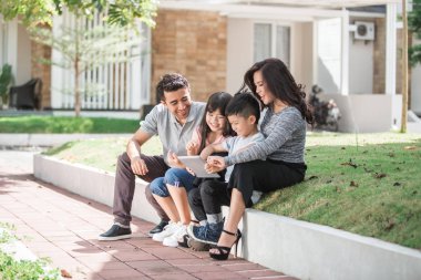 family in front of their house using tablet clipart