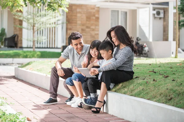 Family in front of their house using tablet — Stock Photo, Image