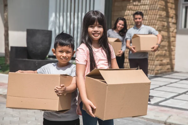 Karton kutu ayakta evin önünde çocuklarla — Stok fotoğraf
