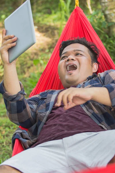 Hombre usando la PC de la tableta en hamaca — Foto de Stock