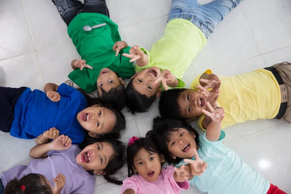 Grupo Niños Pequeños Emocionados Tumbados Suelo Con Amigo Hacer Círculo —  Fotos de Stock