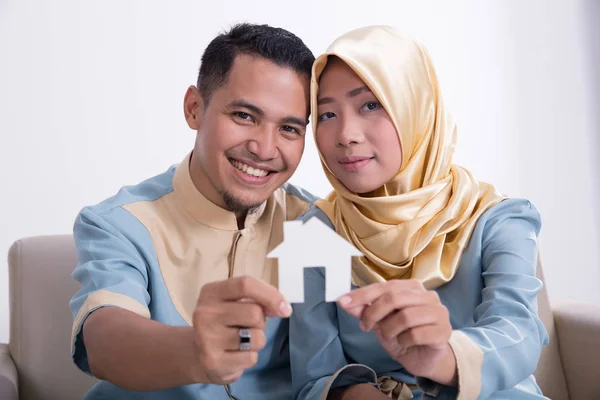 Мусульманская азиатская пара держит дома знак — стоковое фото