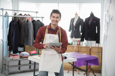 mutlu Genç Asyalı moda tasarımcısı öğe, dikey, ofisinde ise kameraya gülümseyen tablet