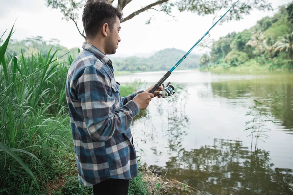 Man op de rivieroever visserij vis — Stockfoto