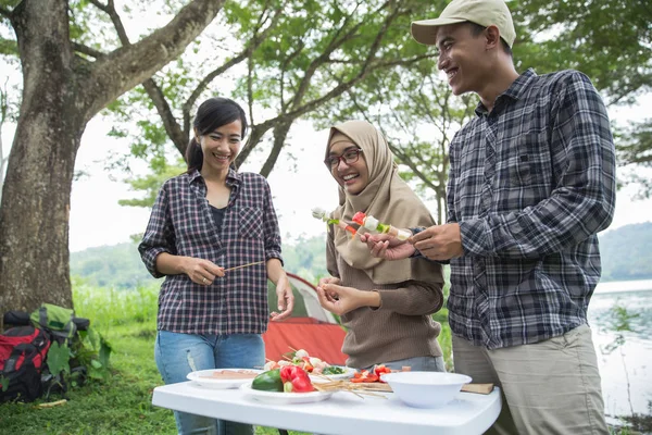 Preparing food with skewers during outing — Stock Photo, Image