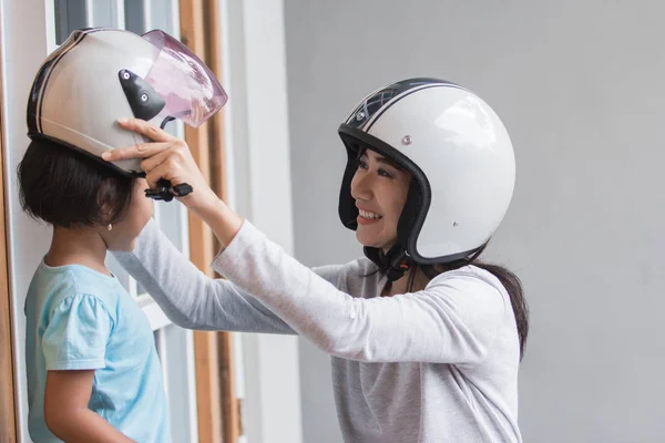 mom help her daughter to wear a helmet before riding a motor bike