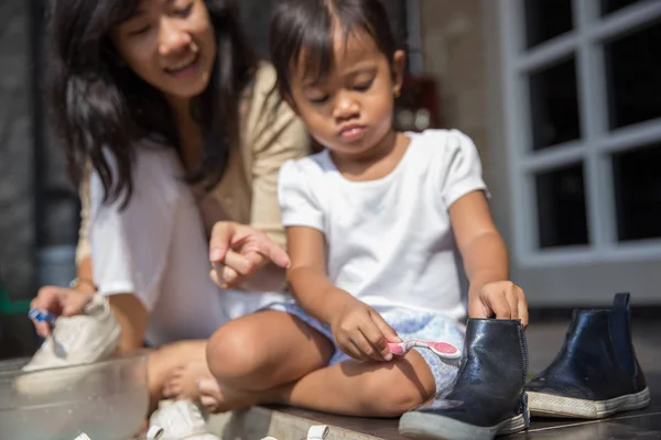 Madre con su niña lavando sus zapatos juntos — Foto de Stock