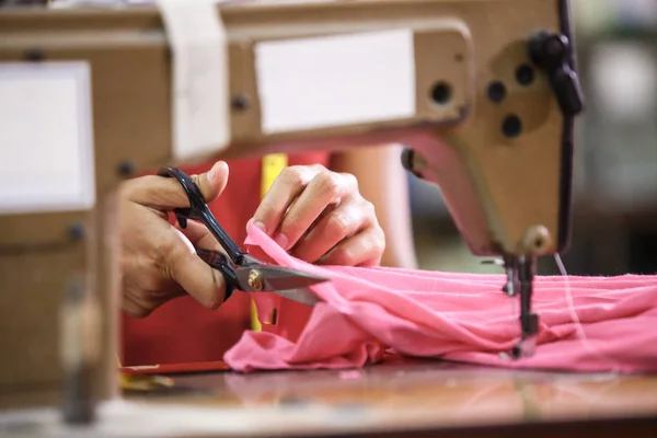 Mãos de homem cortando um tecido em uma fábrica de roupas — Fotografia de Stock
