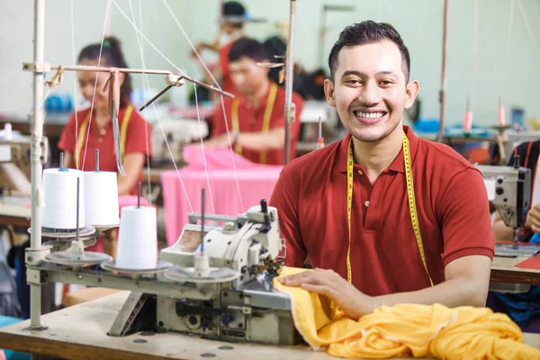 asian worker in textile factory sewing using industrial sewing m