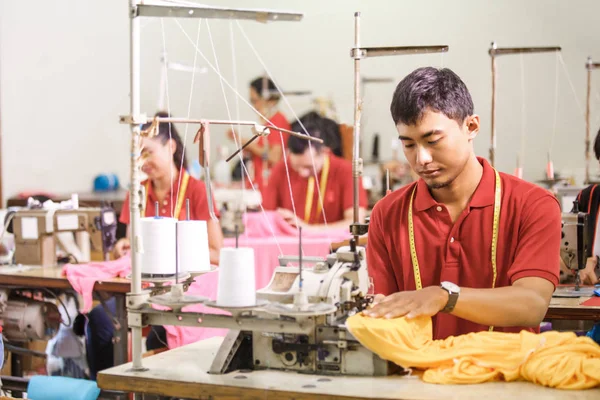 man sewing on a sewing machine at a clothing factory