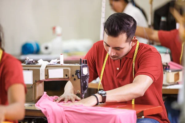 Homem costura em uma máquina de costura em uma fábrica de roupas — Fotografia de Stock