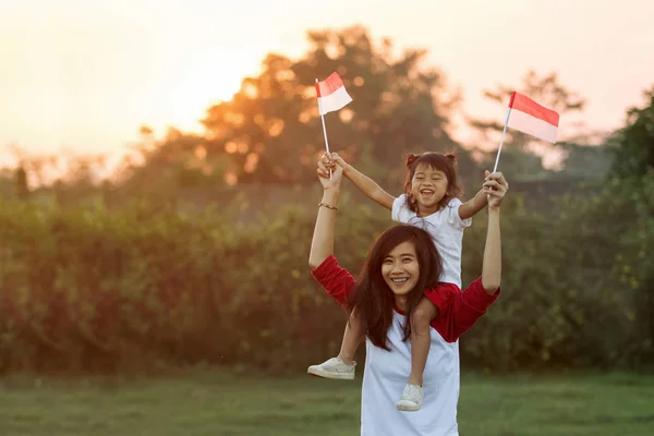 Anne ve kızı Endonezya bayrağı yükseltmek — Stok fotoğraf