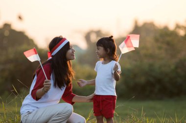 mother and daughter raising flag of indonesia clipart