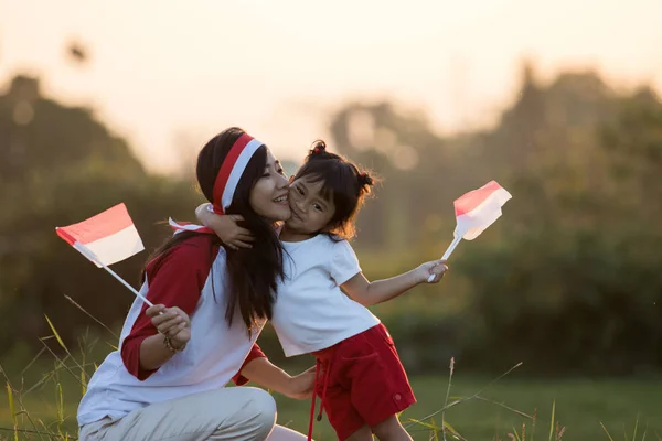 Moeder en dochter verhogen van de vlag van Indonesië — Stockfoto