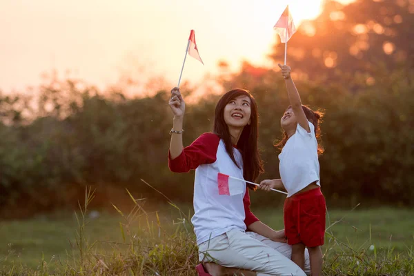 Madre e figlia alzando bandiera di indonesia — Foto Stock