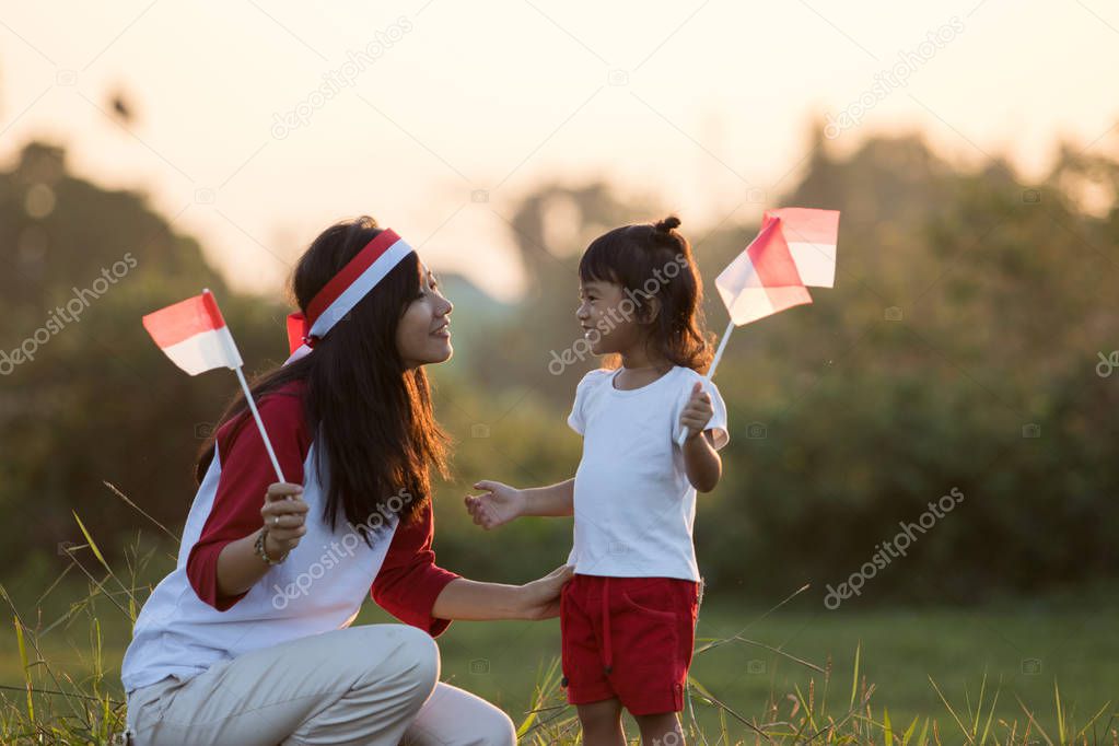 mother and daughter raising flag of indonesia
