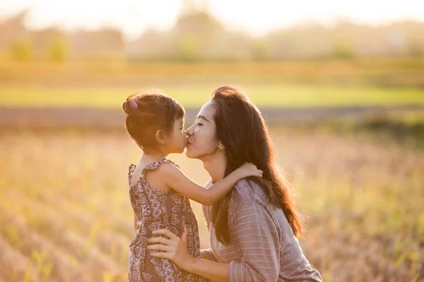 mother and daughter kissing in the field