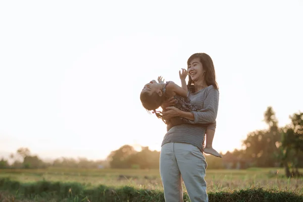 Mamá y el niño abrazándose bajo el cielo del atardecer — Foto de Stock