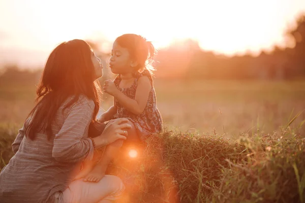 Mamá y su hija en un hermoso paisaje de puesta de sol — Foto de Stock