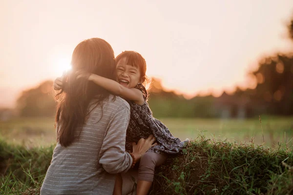 Máma a dítě objímání podle západu slunce na obloze — Stock fotografie