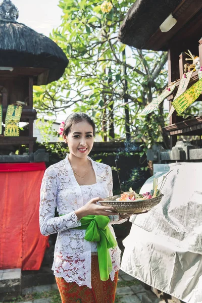 Mujer balinesa vistiendo ropa tradicional trayendo canang sari — Foto de Stock