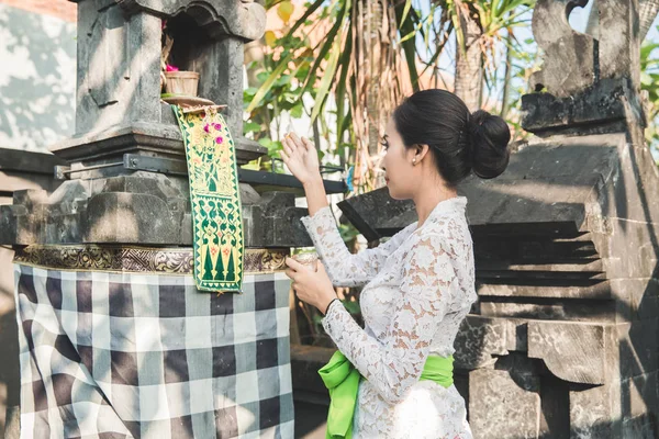 Balinese woman doing ritual offering canang sari and praying at — Stock Photo, Image