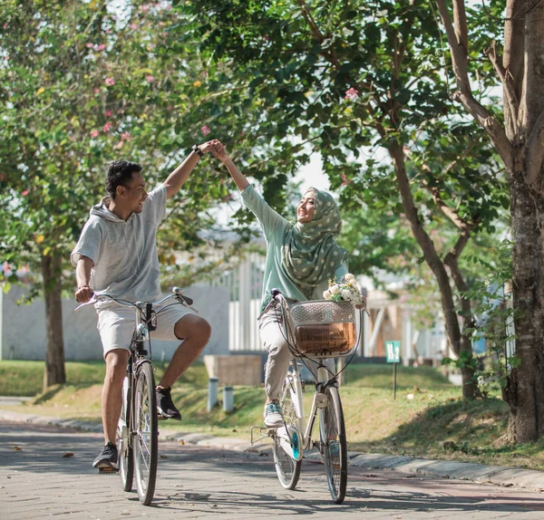 Пара, держащаяся за руки во время езды на велосипеде — стоковое фото