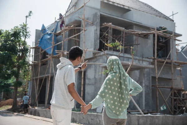 Мусульманська пара перед незакінченим будинком — стокове фото
