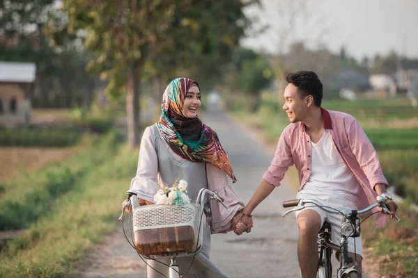 Couple holding hands while ride a bike — Stock Photo, Image