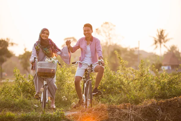 Couple holding hands while ride a bike — Stock Photo, Image