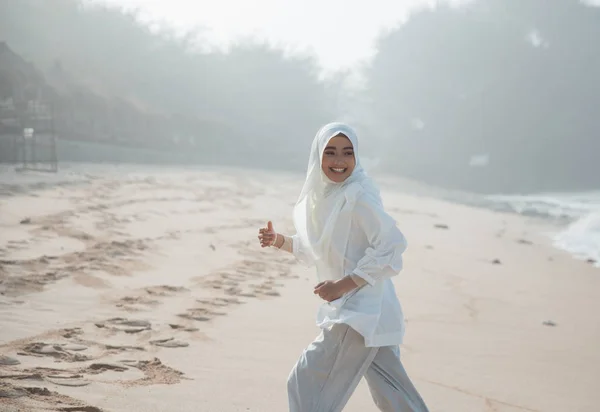 ビーチを楽しんで実行しているイスラム教徒の女性 — ストック写真