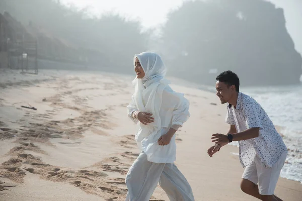 若い男と一緒にビーチで走っている女性の肖像画 — ストック写真