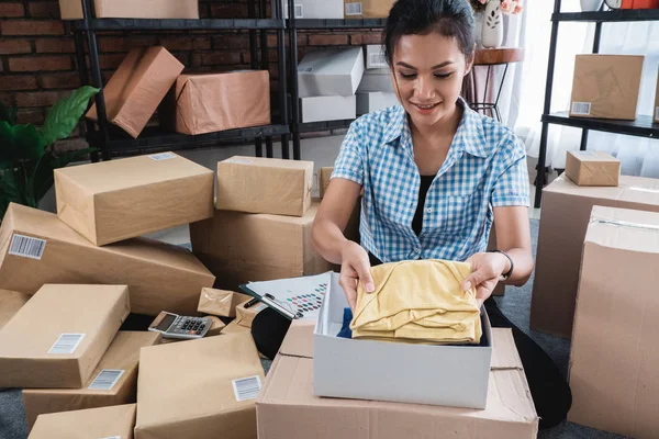 Jonge vrouw verpakken van kleren op de vakken — Stockfoto